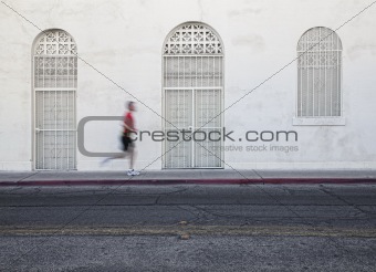 Fast paced man runs down city street.