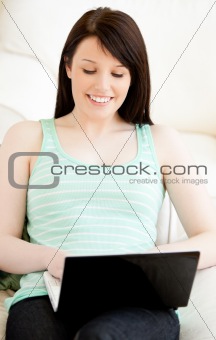 Brunette caucasian teenager using her laptop on the sofa 