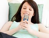 Delighted teenager sending a text message lying on the sofa