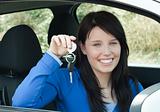 Radiant teenager holding car keys sitting in her new car