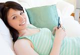 Smiling female teenager lying on a sofa writing messages