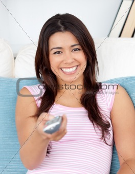 Captivating asian woman holding a remote smiling at the camera