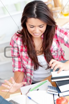 Stressed student doing her homework sitting at the desk