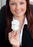 Happy businesswoman holding a light bulb smiling at the camera 