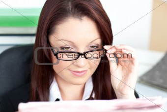 Delighted businesswoman reading a newspaper wearing glasses 