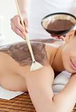 Charming woman enjoying a mud skin treatment 