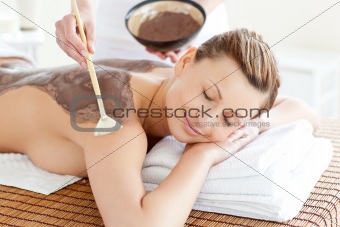 Relaxed woman enjoying a mud skin treatment 