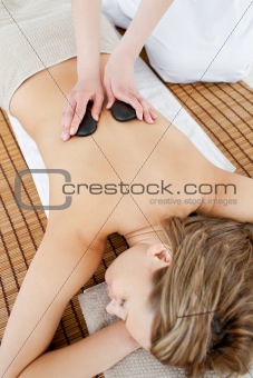 Positive woman having a massage in a spa with hot stones