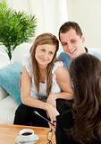 Affectionate couple listen to a saleswoman siting on a sofa