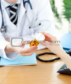 Close-up of an assertive male doctor giving pills to his patient during a visit