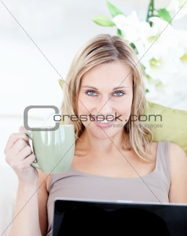 Woman sitting in front of her laptop and holding a cup