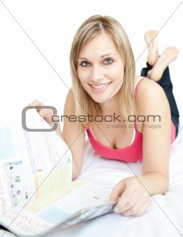 Beautiful happy woman reading a magazine in bed