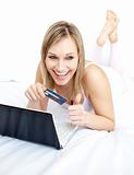 Laughing woman lying with a laptop on sofa