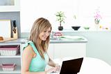 Bright woman using her laptop in the kitchen