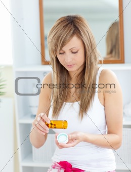 Serious woman taking pills in the bathroom