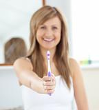 Smiling woman holding a toothbrush into the camera 