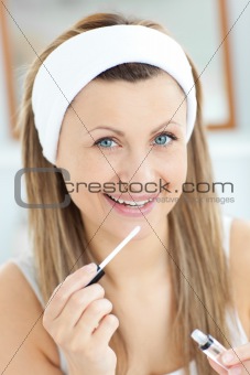 Delighted woman applying gloss on her lips 