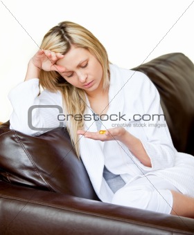 Exhausted woman have a headache and look at pills against a white background