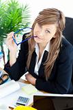 Thougtful businesswoman holding glasses sitting at her desk