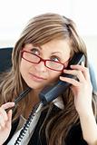 Pensive businesswoman talking on phone wearing glasses 