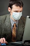 Man in medical mask works with laptop