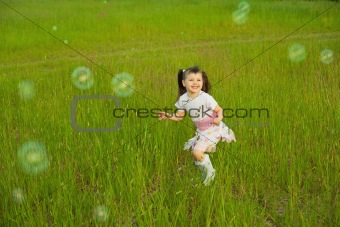 Happy little girl among soap bubbles