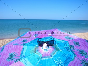 Sunglasses and sunshade on the summer beach