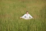 Man in kimono meditates sitting in grass