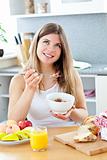 Glowing brunette woman eating cereals with raspberrie in the kit