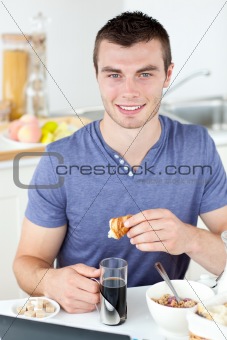 Handsome man eating croissant drinking coffee 