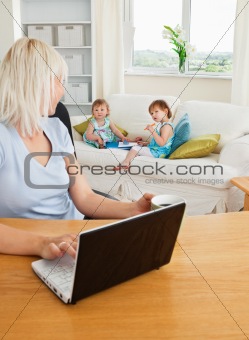 Blond mother working at laptop