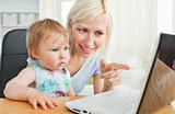 Blond mother having fun with her daughter in front of the laptop