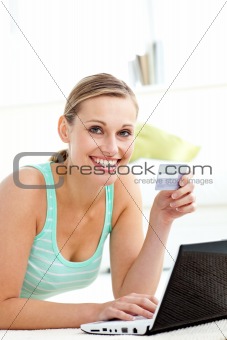 Happy young woman using her laptop holding a card