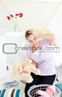 Blond young woman with headache putting toys into a basket