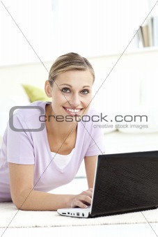 Charming woman using her computer lying on the floor 
