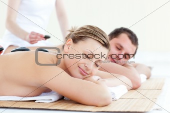 Positive young couple receiving a back massage with hot stones in a Spa center