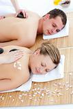 Attractive young couple receiving a back massage with hot stones in a Spa center