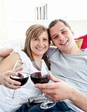 Loving young couple drinking wine sitting on a sofa 