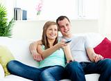 Charismatic man embracing his girlfriend while watching tv 