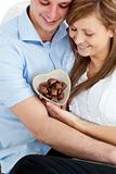 Loving man giving chocolates to his girlfriend against a white background