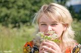 Beautiful girl in fresh grass smelling flower