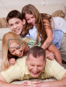 Happy family of four having fun in bed