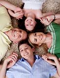 Happy family of four lying on the carpet