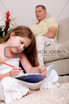 Cute girl studying with her father in the background