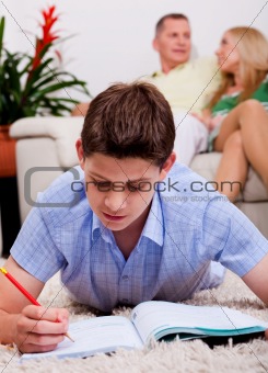 Young boy studying with family in the background