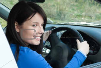 Happy female teenager sitting in her new car