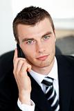 Assertive young businessman talking on phone looking at the came