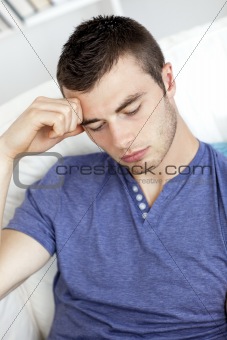 Tired caucasian man sitting on the sofa 