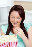 Laughing woman sitting on sofa with popcorn