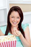 Charming woman sitting on sofa with popcorn